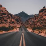 black concrete road surrounded by brown rocks